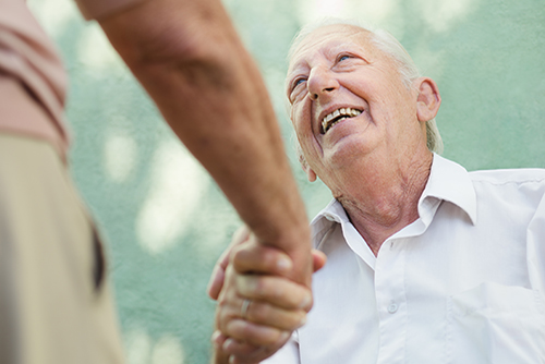 Elderly man looking up at man he's shaking hands with