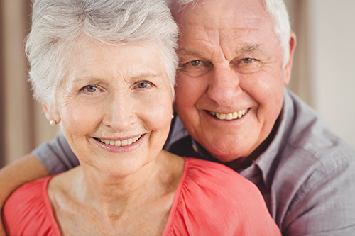 Close up of elderly couple sitting closely smiling at the camera